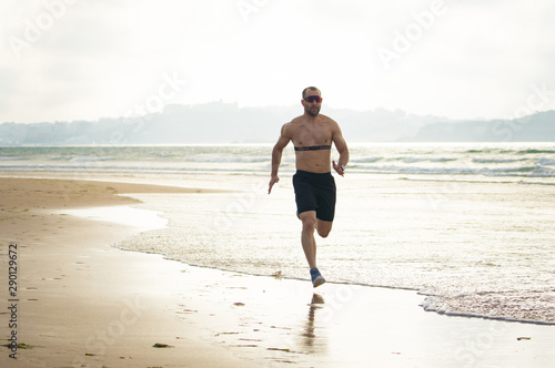 Professional athlete runner man running using heart rate monitor and smart watch training on beach