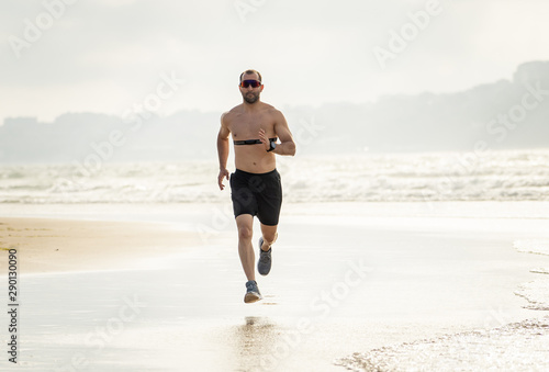 Fitness sports man using heart rate monitor running on beach