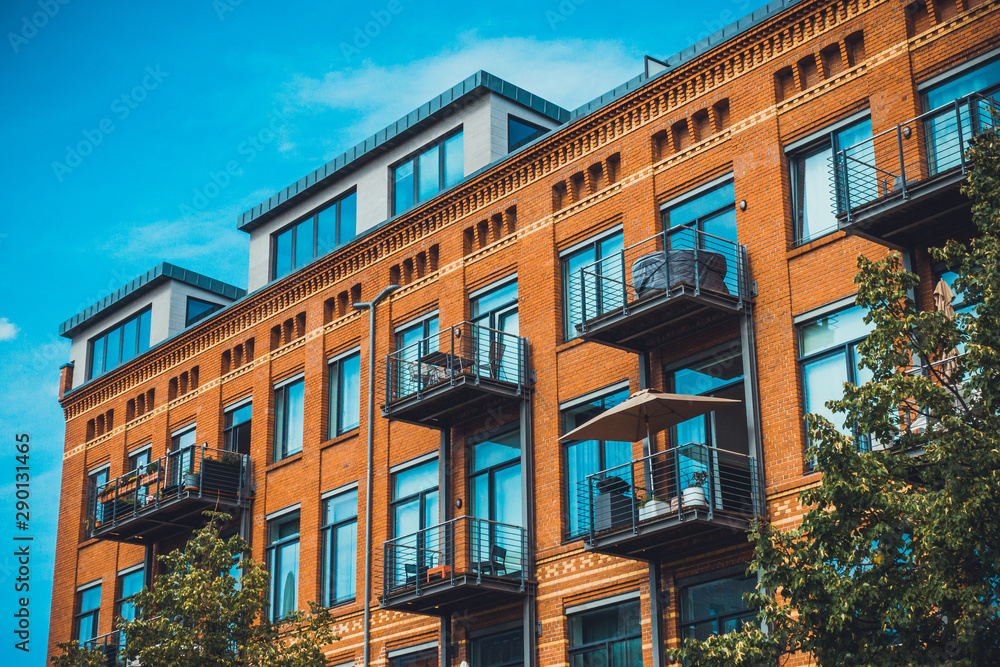 Naklejka premium orange apartment building with brick facade and steel balcony