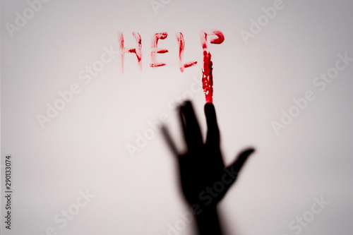 Hand writing HELP in red blood behind frosted glass window
