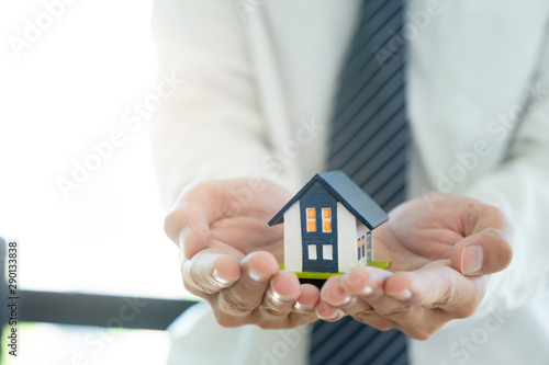Business man hand hold the house model saving small house. House insurance.