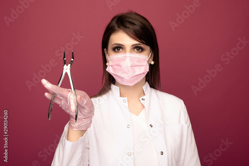 Portrait of female dentist holding dental stuff isolated over the pink studio photo