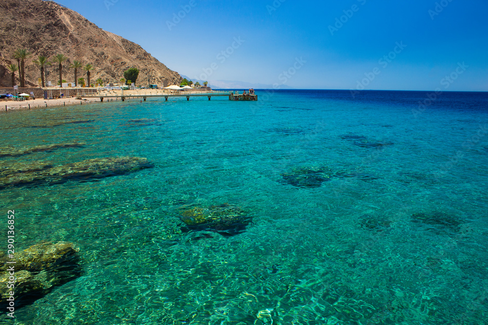 Red sea scenery landscape view beautiful tropic summer vacation destination place aquamarine transparent water with coral reefs bottom and desert mountains and pier with people background 