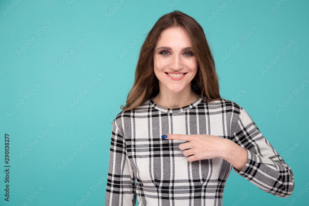 Happy girl pointing something standing isolated over the blue background Happy girl pointing something standing isolated over the blue background