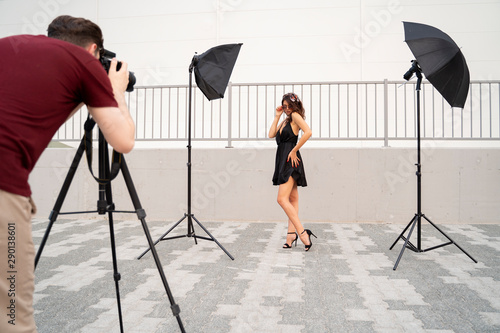 Behind the scene male photographer and attractive female photo model on set 
