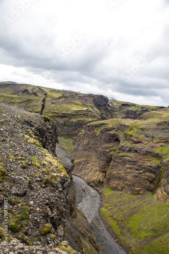 Landmannalaugar, Iceland »; August 2017: A young man on a cliff on the Landmannalaugar trekking looking at the bottom