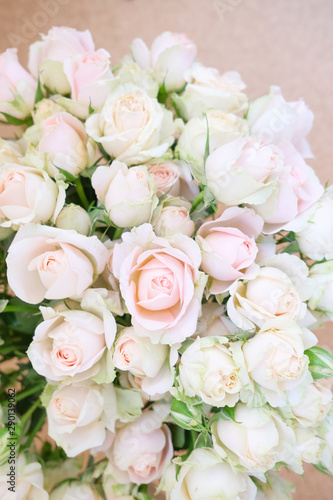 A bouquet of fresh tea and gently pink roses on a beige background.