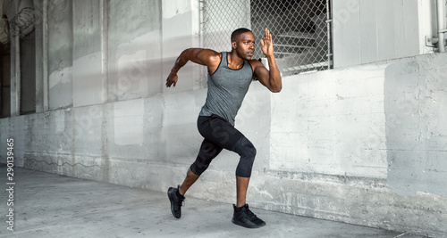 Fotografiet African american male athlete sprinter, running at a high speed in urban concret