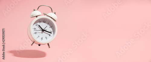 Pink Alarm clock on pastel pink background. photo