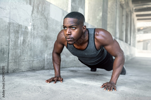 Fotografía Black male working out alone outside on concrete, pushups in urban downtown city