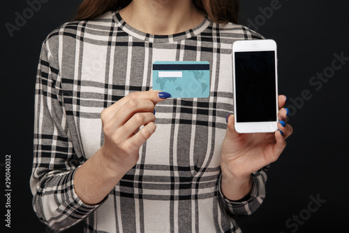 Closeup view of cellphone and credit plastic card in woman's hands