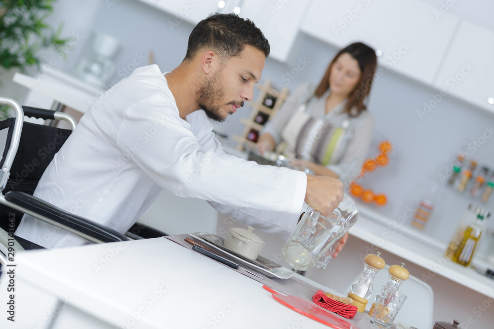 Fototapeta premium man on the wheelchair serving himself with water