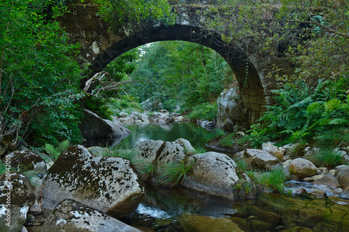 Antique arched stone bridge over Gralheira river in Carvalhais, Sao Pedro do Sul, Portugal photo