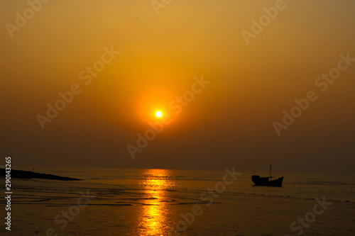 A beautiful and golden sunset in the river with a fishing boat