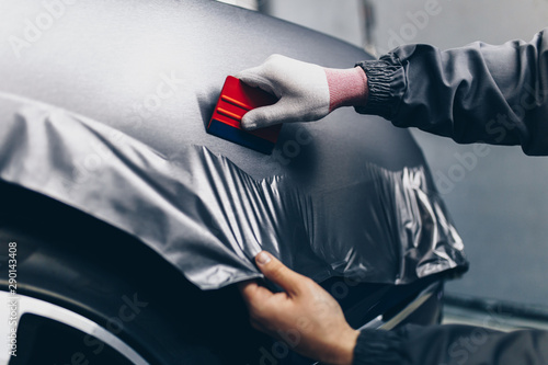 Car wrapping specialist putting vinyl foil or film on car. Selective focus. photo