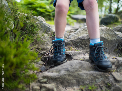 5 year old boys legs with hiking boots descends rocky path