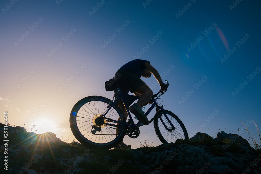 Silhouette of a mountain biker riding his mountain sportbike on top of a cliff ( hill).