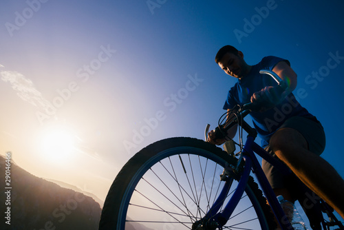 Fototapeta Naklejka Na Ścianę i Meble -  Close up silhouette of an athlete (mountain biker) riding his bike on rocky mountains.