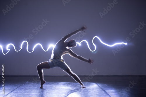 Modern Dance performer dancing with a neon blue light while making gracious moves and spectacular body art expressions. photo