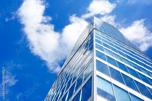 High-rise glass building on a background of blue sky and clouds.