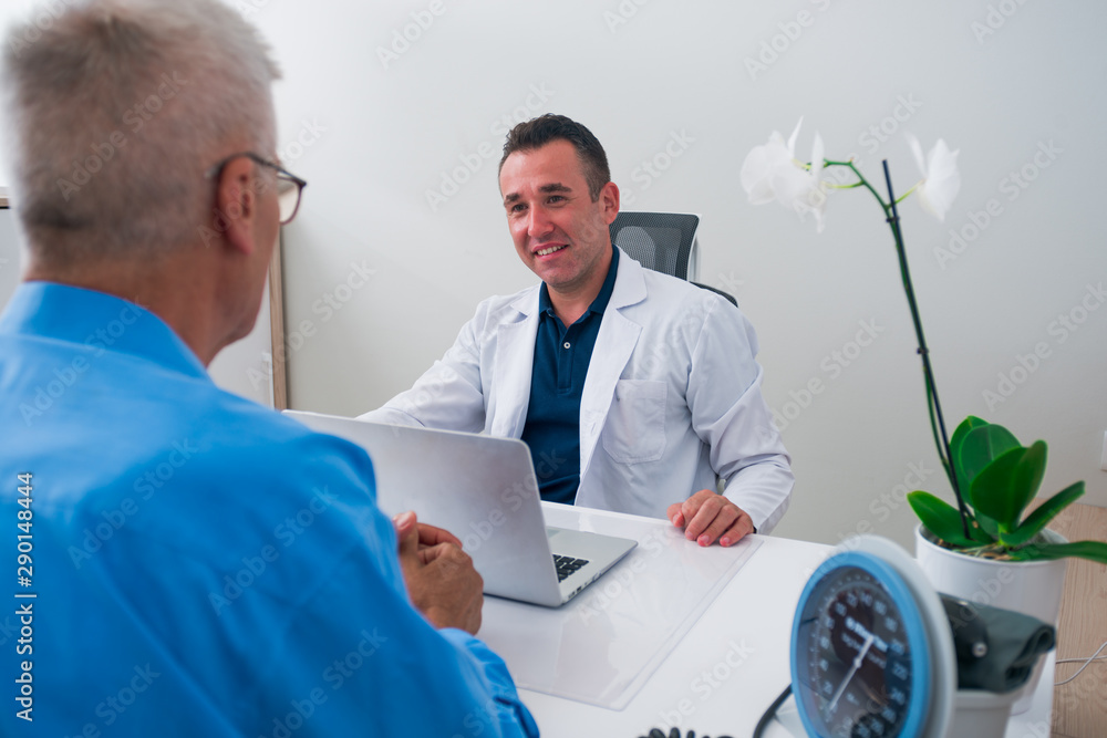 Obraz premium Handsome Doctor and his senior (older) patient discussing the symptoms the older gentleman has, and the illness he might have.