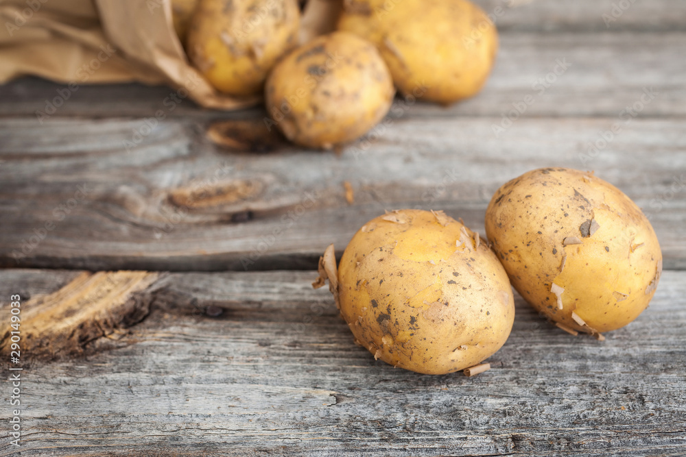 Raw potato. Fresh new potatoes in kraft paper bag on wooden background Raw potato. Fresh new potatoes in kraft paper bag on wooden background