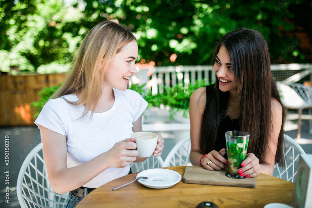 Two young happy friends having drinks in cafe Two young happy friends having drinks in cafe