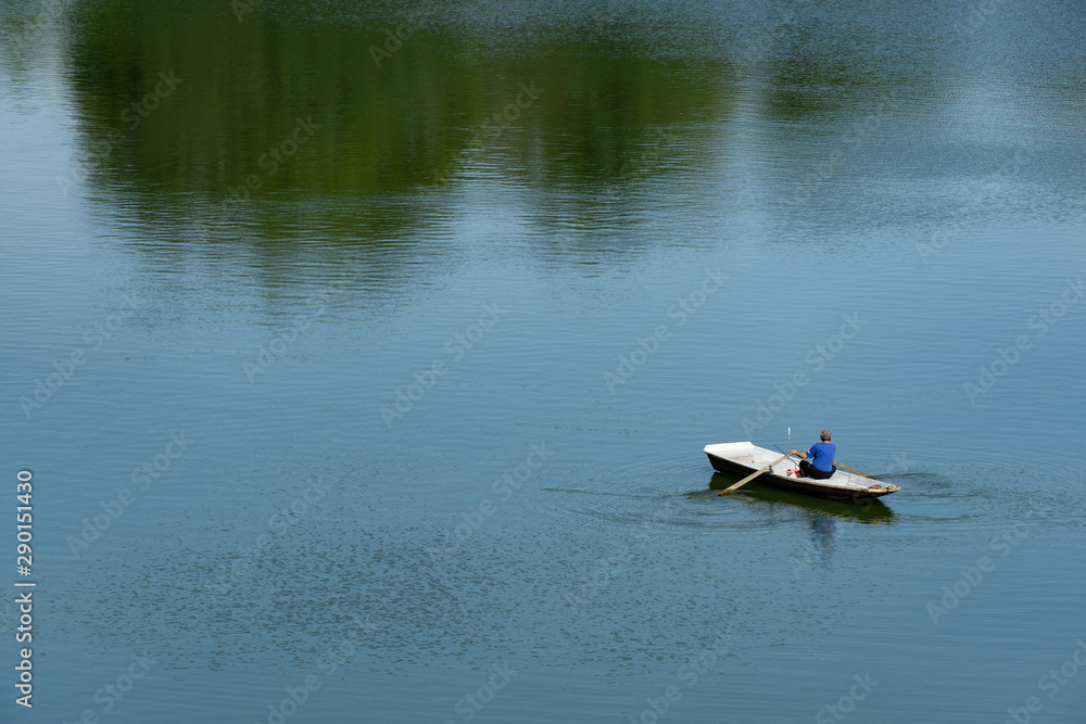 Fisherman rowing a boat on pond