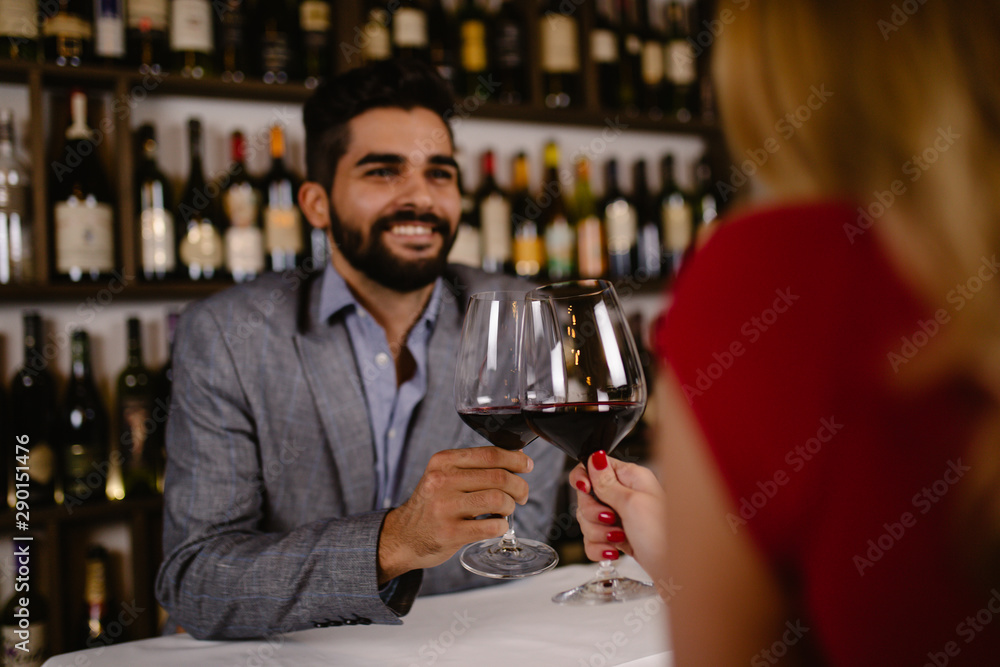 Attractive young couple clinking by wine glasses in restaurant during date.
