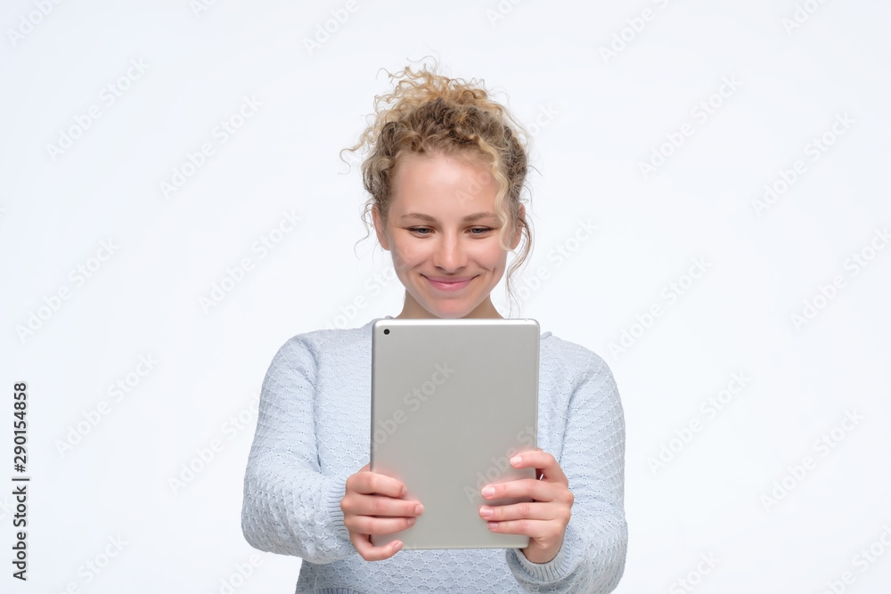 Playful cute young caucasian woman with curly hair making selfie with tablet. Studio shot. Playful cute young caucasian woman with curly hair making selfie with tablet. Studio shot.