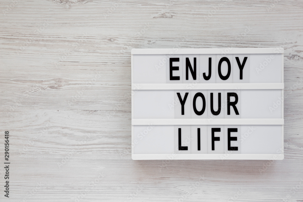 'Enjoy your life' words on a lightbox over white wooden surface, overhead view. Top view, from above. Flat lay. Copy space. 'Enjoy your life' words on a lightbox over white wooden surface, overhead view. Top view, from above. Flat lay. Copy space.