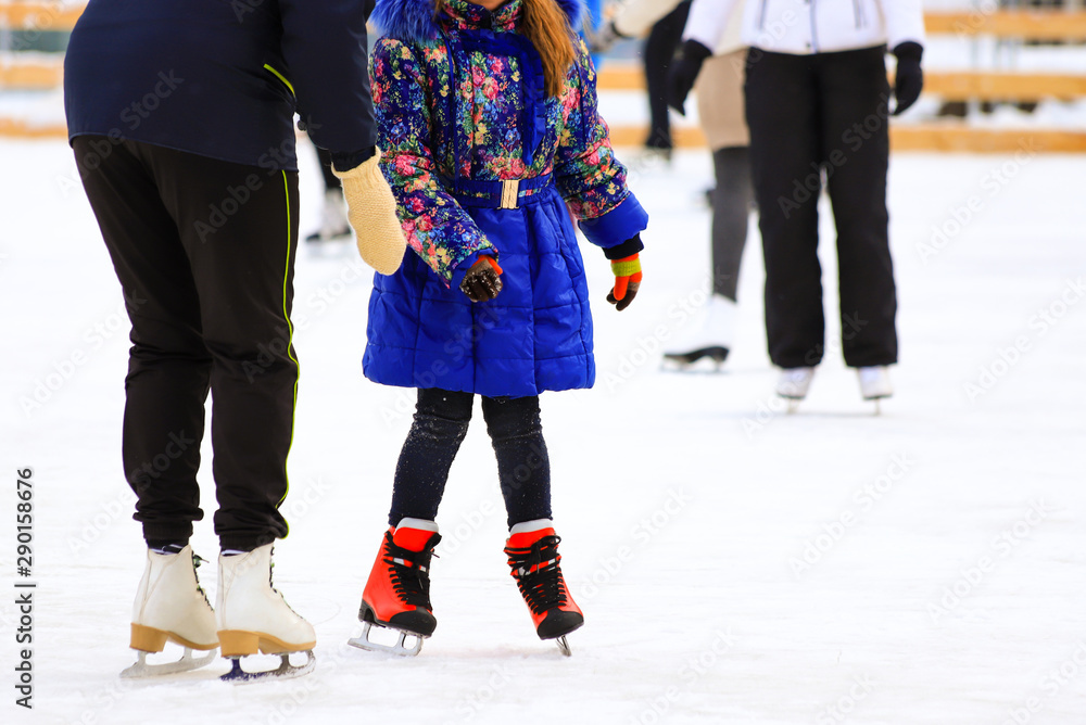 A girl in a jacket rides with her mom in the winter rink. Active family sports, children's winter holidays, sports club A girl in a jacket rides with her mom in the winter rink. Active family sports, children's winter holidays, sports club