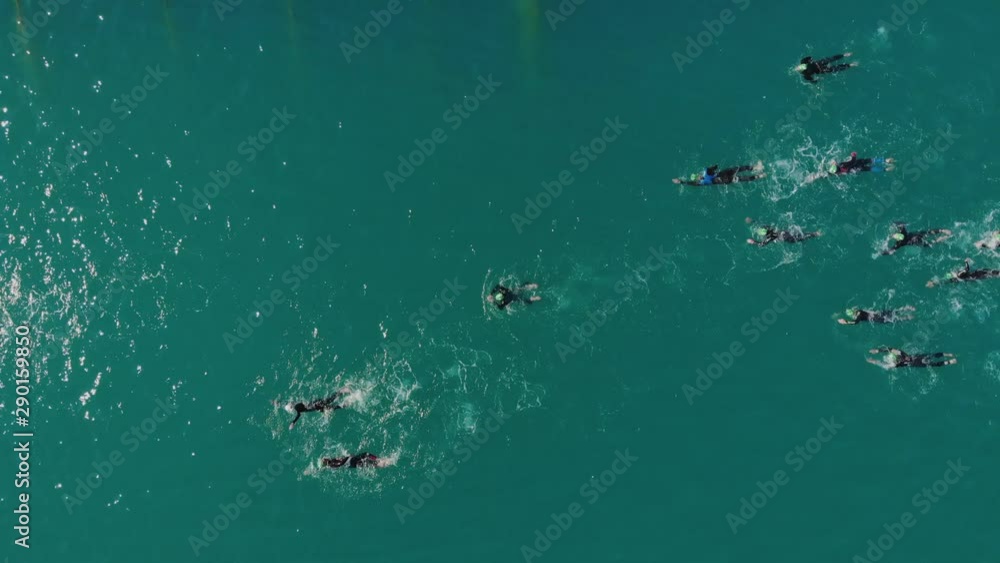 Fly over swimmers in wetsuite in sea, drone top view Outdoor swimming in open water. During sunny summer day. Fly over swimmers in wetsuite in sea, drone top view Outdoor swimming in open water. During sunny summer day.