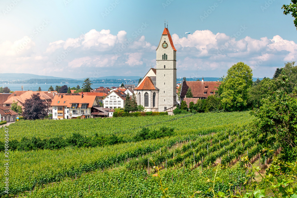Panoramic view of lake of Lake Constance. Zeppelin, apple trees and Catholic Church St. Johann Baptist in Hagnau on the picture. Panoramic view of lake of Lake Constance. Zeppelin, apple trees and Catholic Church St. Johann Baptist in Hagnau on the picture.