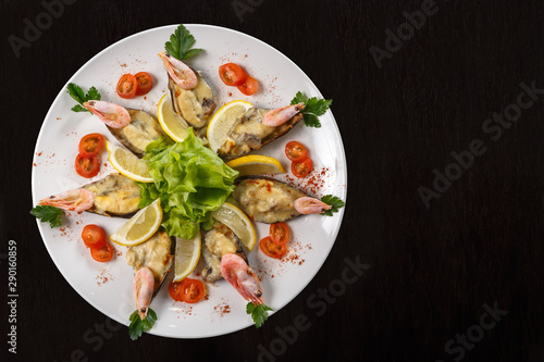 A dish of shrimp, tomatoes, lettuce and lemon