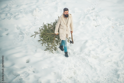 Woodcutter with axe in the winter forest. Purchase and delivery of conifer on Christmas Eve. Winter portrait of lumber in snow Garden cutting Christmas tree.