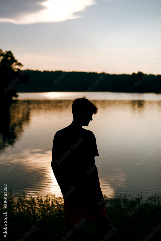 Silhouette of young man at a lake during sunset Silhouette of young man at a lake during sunset
