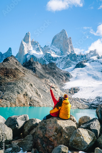 Couple in love on Mount Fitzroy, Patagonia trek. Scenic view of snowcapped mountain tops. Blue sky, turquoise lake and scenic rock landscape. Shot in Argentina. Nature, travel, adventure, hiking. photo