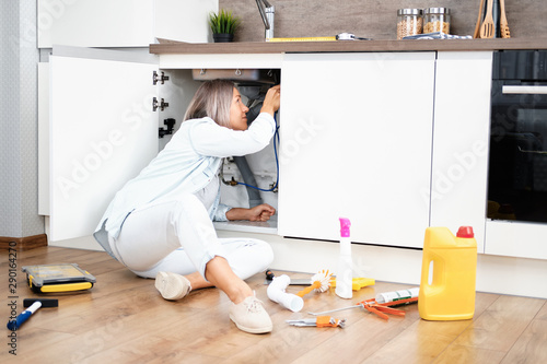 Woman fixing kitchen sink photo