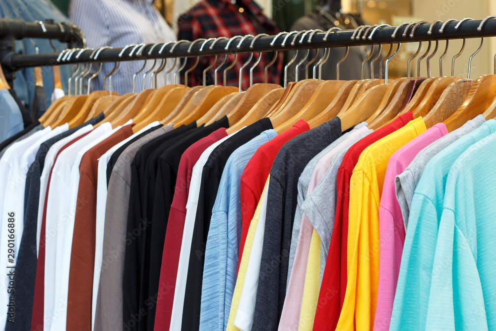 Multi-colored t-shirts with long sleeves on wooden hangers, side view.