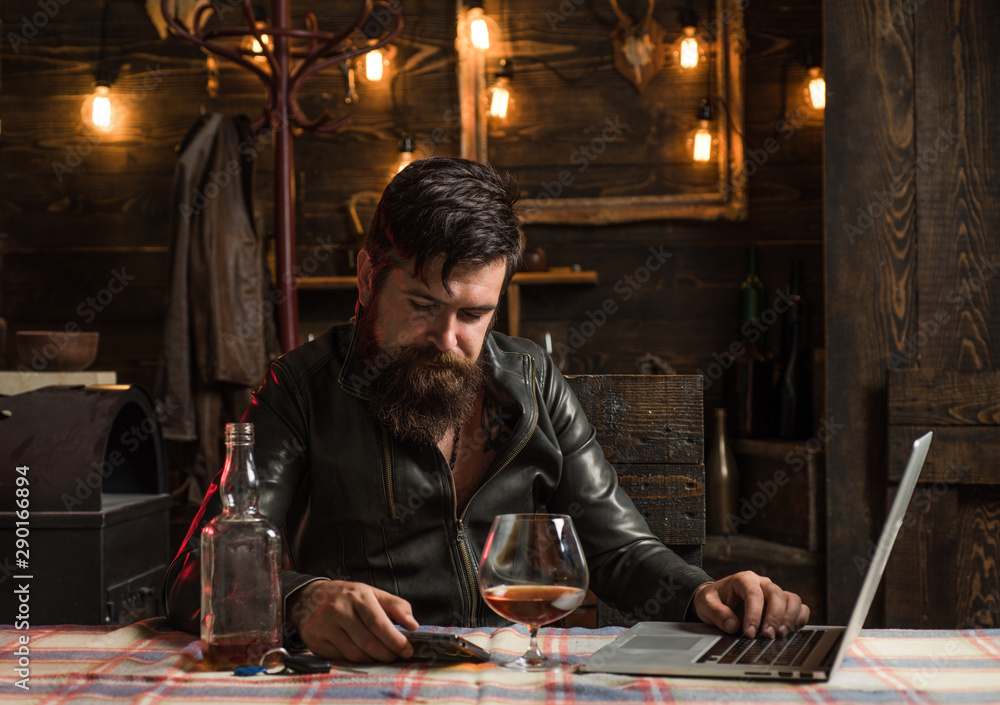 Drinking man is cheking his phone. Man with beard holds glass brandy. Man holding a glass of whisky. Sipping whiskey. Degustation, tasting. Macho is drinking whiskey by his laptop. Tired. Drinking man is cheking his phone. Man with beard holds glass brandy. Man holding a glass of whisky. Sipping whiskey. Degustation, tasting. Macho is drinking whiskey by his laptop. Tired.