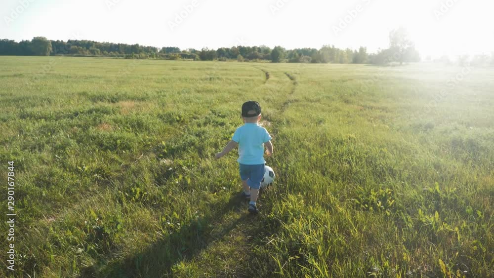 Small boy playing with ball in football at sunset in field. Small boy playing with ball in football at sunset in field.