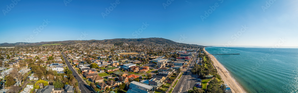 Wide aerial panoramic landscape of Dromana coastline, suburb and pier on bright sunny afternoon