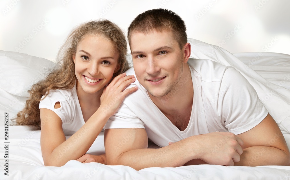 Dissatisfied beautiful young woman in bed with sad expression on her face, sex problems in long relationship or marriage while man sleeping. Saturation or satiety between caucasian couple, disinterest