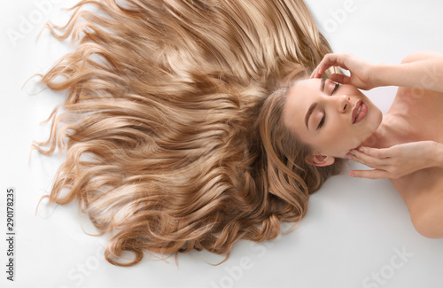 Young woman with beautiful curly hair on light background