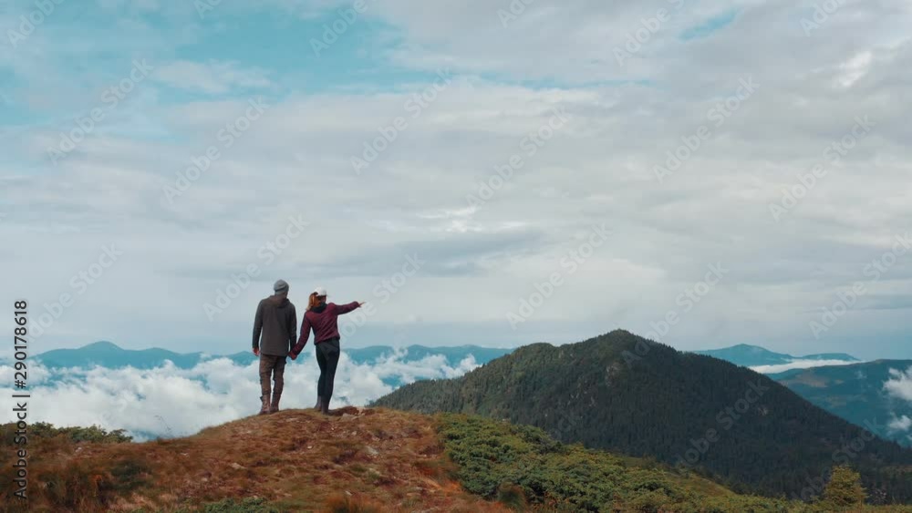The man and woman standing on a mountain with a beautiful landscape The man and woman standing on a mountain with a beautiful landscape