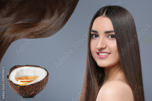 Young woman with beautiful long hair and coconut oil on grey background