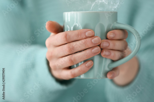 Young woman holding cup of coffee, closeup