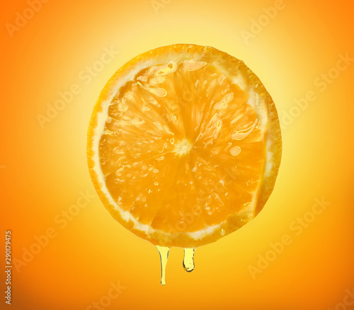 Essential oil dripping from orange slice on white background