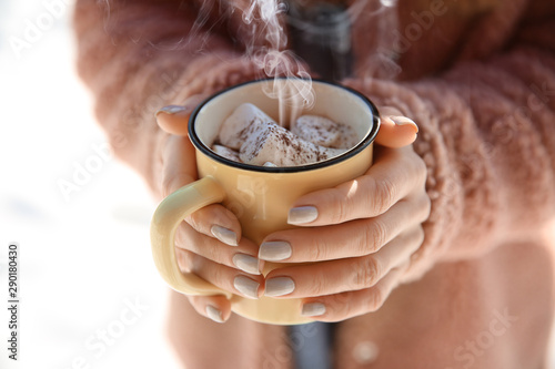 Woman with cup of hot cacao and marshmallows outdoors, closeup
